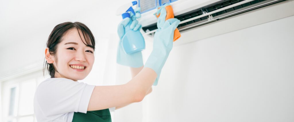 主婦でも簡単に３０分でできるエアコンクリーニングセルフキットを使用してエアコンを掃除している女性